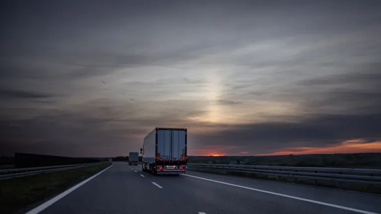 Carreta rodando em rodovia ao entardecer, com o sol se pondo no horizonte