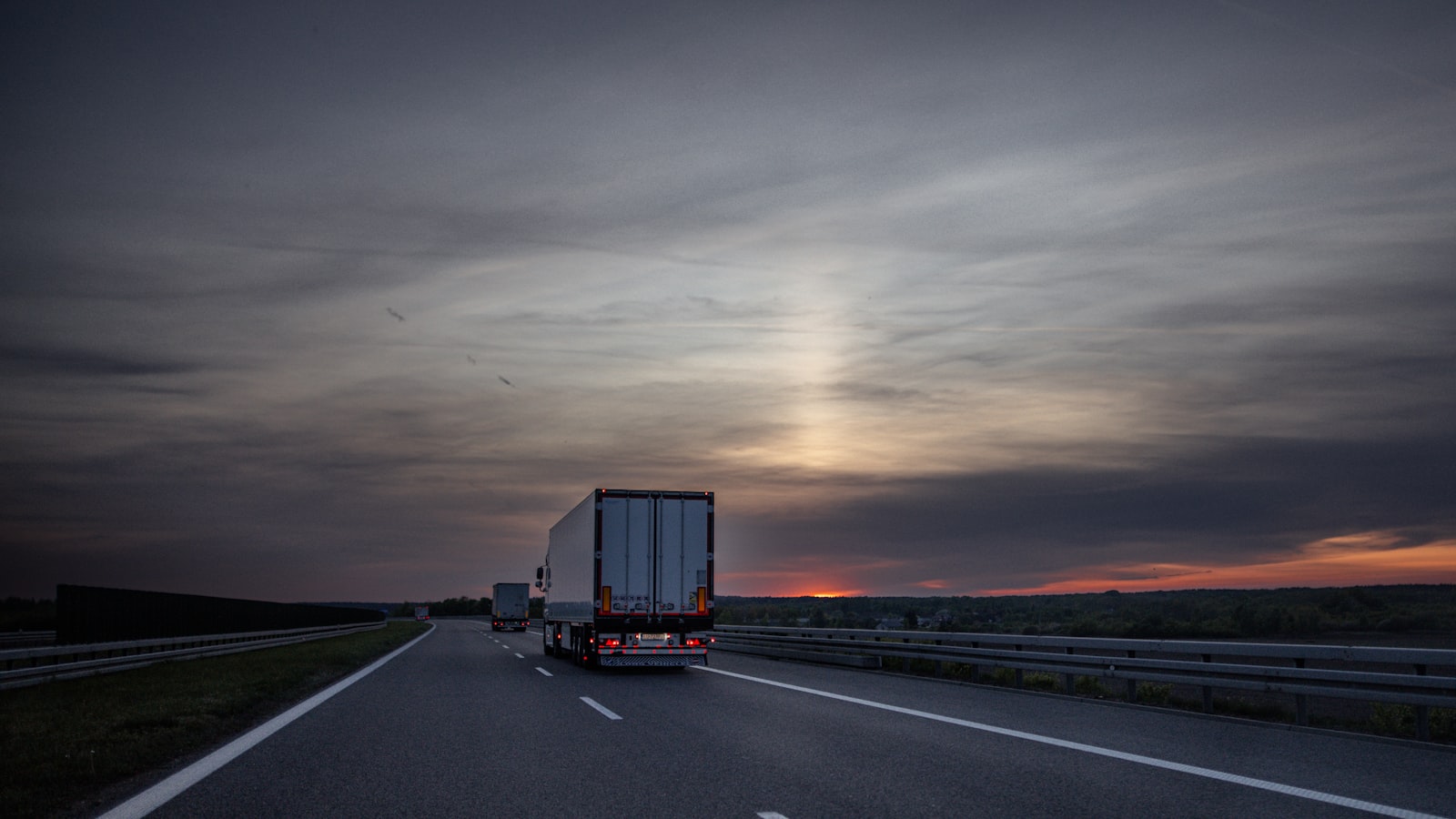 Carreta rodando em rodovia ao entardecer, com o sol se pondo no horizonte